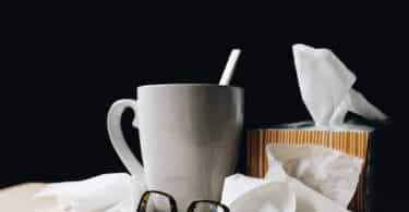 white ceramic mug on white table beside black eyeglasses